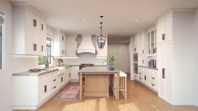 kitchen featuring a kitchen island, white cabinets, backsplash, and premium range hood