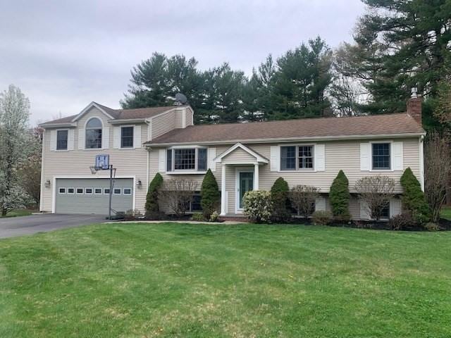 bi-level home with a chimney, a garage, a front lawn, and driveway