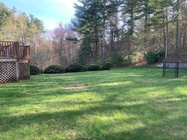view of yard featuring fence, a deck, and a wooded view