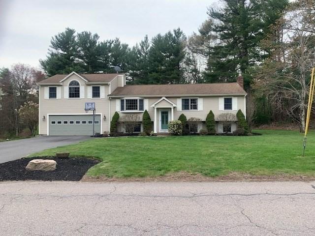 view of front of property with a chimney, aphalt driveway, a front lawn, and a garage