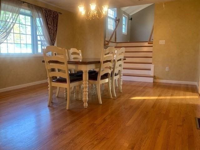 dining room with a notable chandelier, stairway, wood finished floors, and baseboards