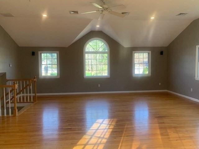 empty room featuring light wood-style flooring, visible vents, baseboards, vaulted ceiling, and a ceiling fan
