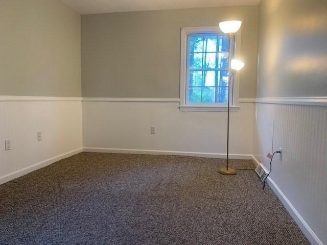 spare room featuring a wainscoted wall and carpet floors