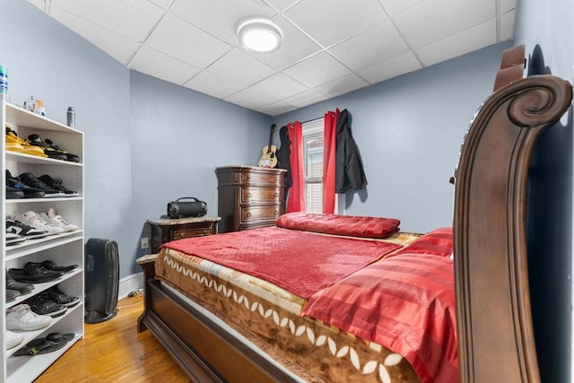 bedroom with a paneled ceiling and light wood-type flooring