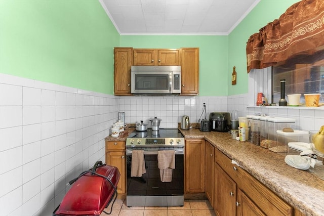 kitchen featuring light tile patterned flooring, tile walls, ornamental molding, light stone counters, and stainless steel appliances