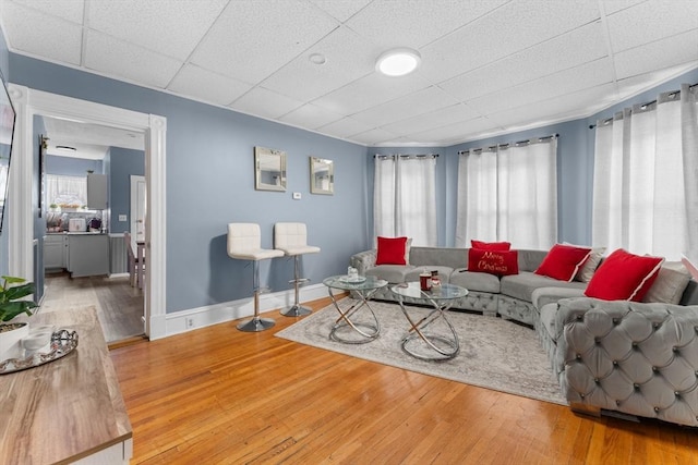 living room featuring a paneled ceiling, plenty of natural light, and hardwood / wood-style floors