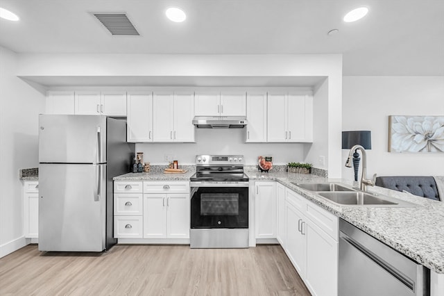 kitchen with light stone counters, white cabinets, sink, stainless steel appliances, and light wood-type flooring