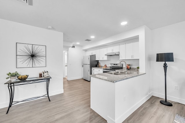 kitchen featuring light wood-type flooring, light stone countertops, stainless steel appliances, white cabinets, and sink