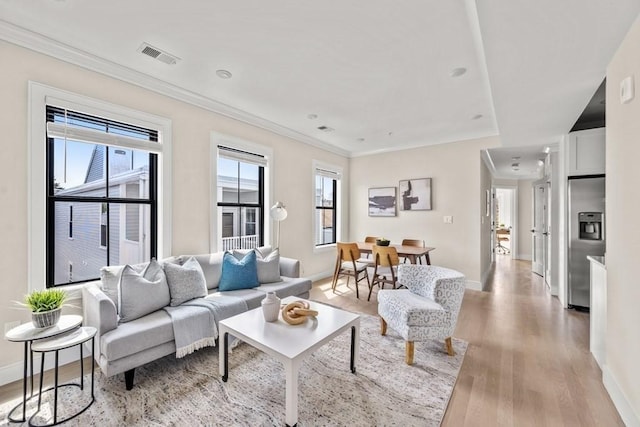 living room featuring ornamental molding, a wealth of natural light, and light hardwood / wood-style flooring