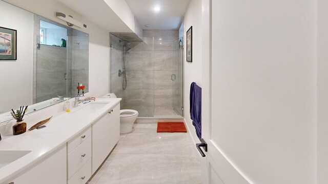 bathroom featuring vanity, a shower with shower door, and toilet