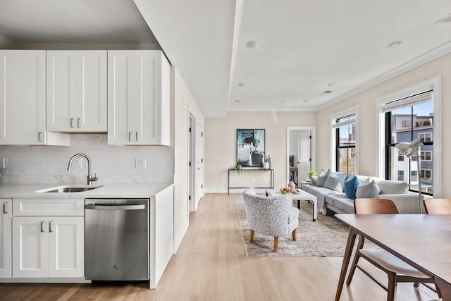 kitchen featuring dishwasher, white cabinets, sink, light wood-type flooring, and tasteful backsplash