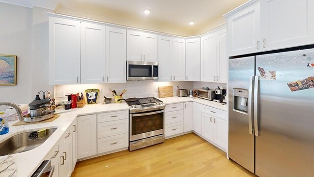 kitchen with white cabinets, stainless steel appliances, light hardwood / wood-style floors, and sink