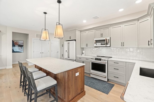 kitchen with white appliances, visible vents, light wood finished floors, a kitchen island, and backsplash