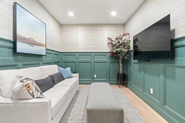 living room featuring a decorative wall, recessed lighting, and light wood-style flooring