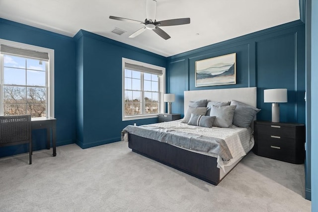 bedroom with visible vents, crown molding, light carpet, a decorative wall, and a ceiling fan