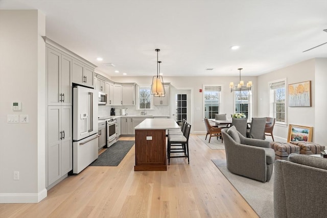 kitchen with open floor plan, electric range oven, high end white fridge, light wood-style floors, and a breakfast bar area