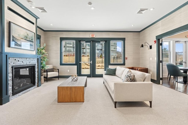 carpeted living area featuring visible vents, a stone fireplace, and crown molding