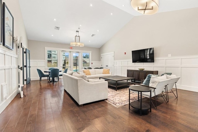 living room featuring french doors, high vaulted ceiling, dark wood-style flooring, and a decorative wall