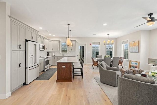 kitchen with white appliances, light wood finished floors, light countertops, a kitchen bar, and open floor plan