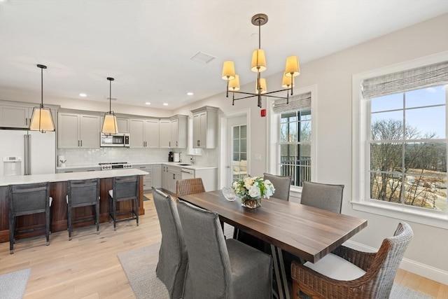 dining area featuring visible vents, baseboards, light wood-style flooring, recessed lighting, and a notable chandelier