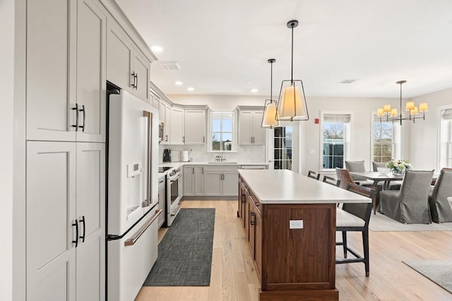 kitchen with visible vents, high end white refrigerator, electric range, a kitchen bar, and a center island