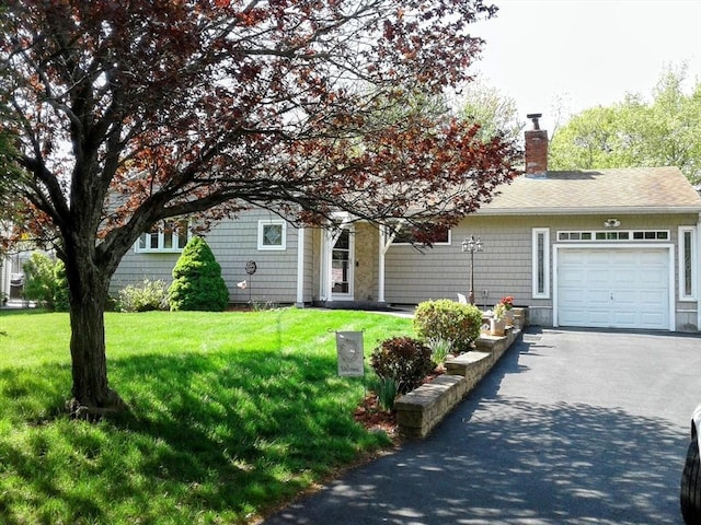 view of front of home with a garage, a chimney, driveway, and a front lawn