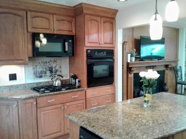 kitchen featuring black appliances, light stone countertops, backsplash, hanging light fixtures, and brown cabinetry