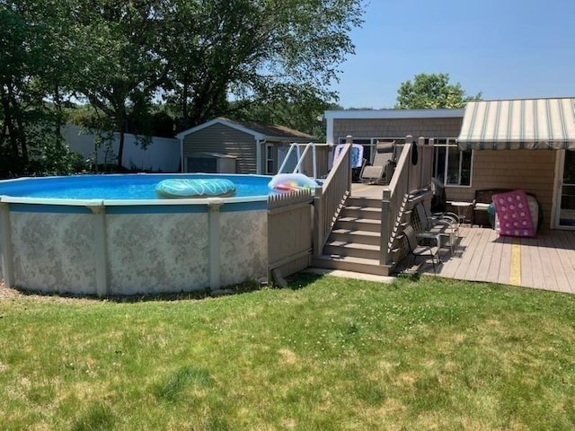 outdoor pool featuring a wooden deck, a yard, and stairs