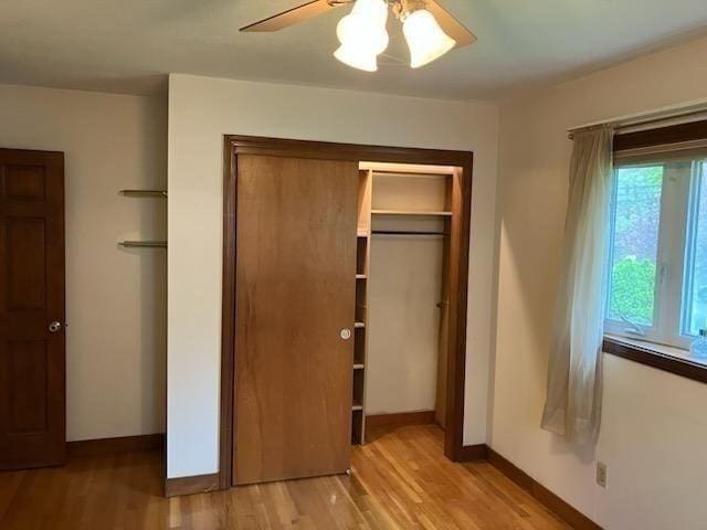 unfurnished bedroom with light wood-style flooring, a closet, baseboards, and ceiling fan