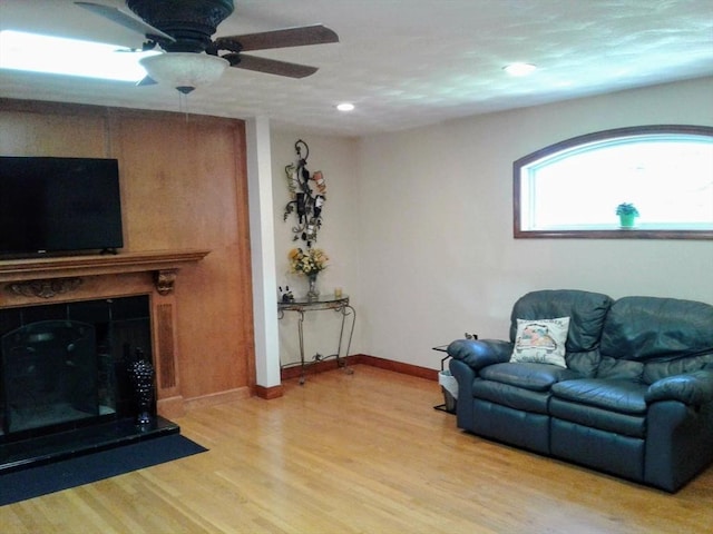 living area featuring light wood-type flooring, a ceiling fan, baseboards, recessed lighting, and a fireplace