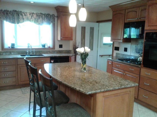 kitchen featuring black appliances, a sink, a center island, a kitchen breakfast bar, and light stone countertops