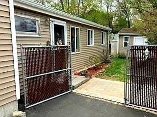 view of side of home with a gate and a storage unit