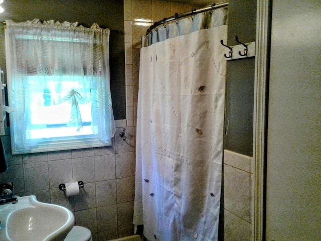 bathroom with a sink, tile walls, and a shower with shower curtain