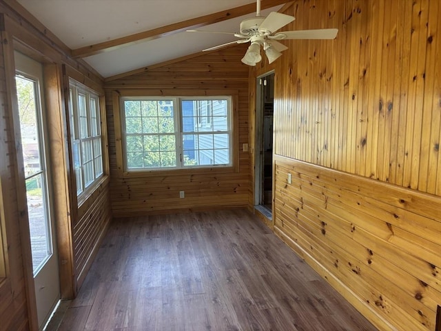 unfurnished room featuring wood walls, lofted ceiling with beams, and a wealth of natural light