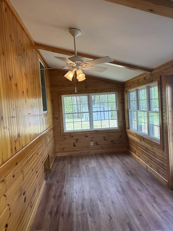 unfurnished room with wood walls, wood finished floors, and vaulted ceiling