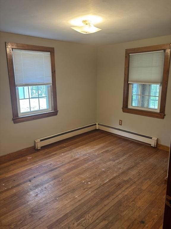 spare room with baseboard heating and dark wood-style floors