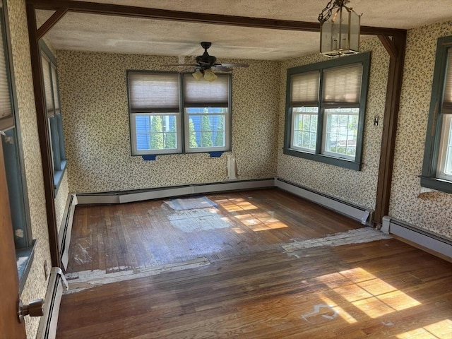 empty room featuring wood-type flooring, a textured ceiling, ceiling fan, and wallpapered walls