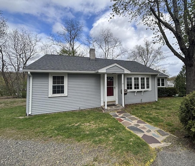 view of front of home featuring a chimney, a shingled roof, and a front lawn