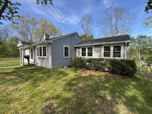 rear view of house featuring a lawn and a chimney
