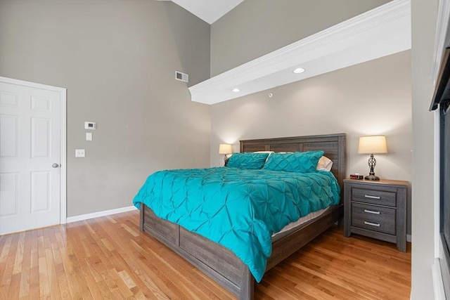 bedroom featuring visible vents, baseboards, a high ceiling, recessed lighting, and light wood finished floors