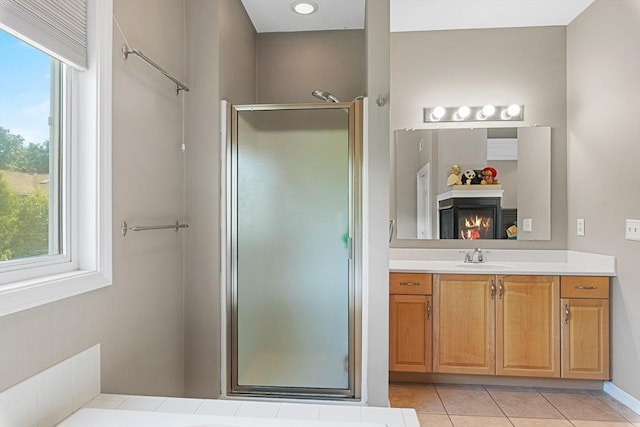 full bathroom with vanity, tile patterned flooring, a shower stall, and a warm lit fireplace