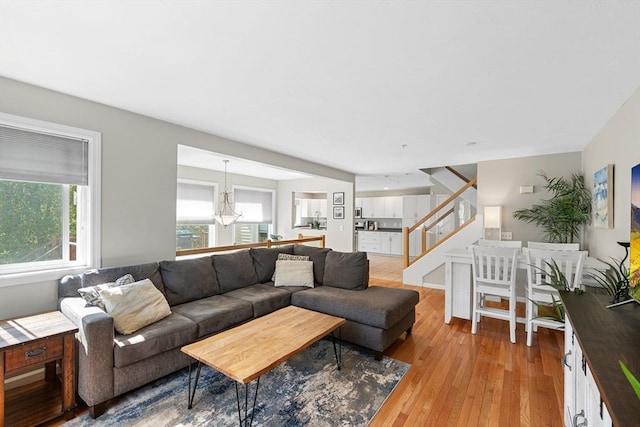living area featuring light wood-type flooring, a notable chandelier, and stairway