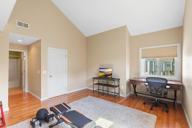 office area with high vaulted ceiling, baseboards, wood finished floors, and visible vents