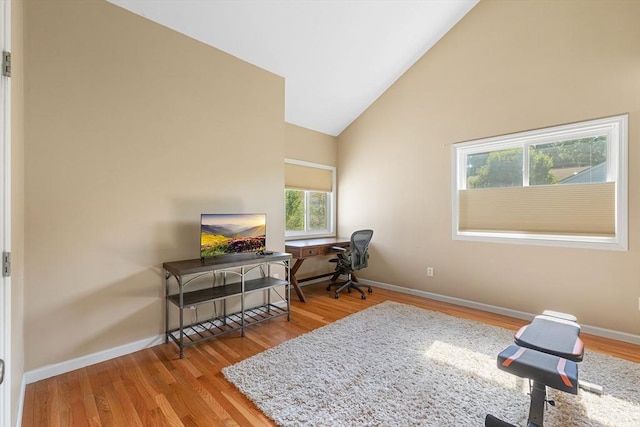 office space with baseboards, wood finished floors, and high vaulted ceiling