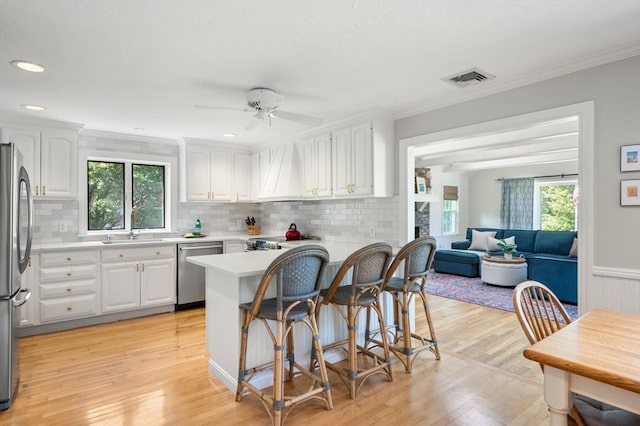 1051 Randolph Ave, Milton, MA 02186 - kitchen featuring stainless steel appliances, plenty of natural light, light countertops, white cabinets, and crown molding