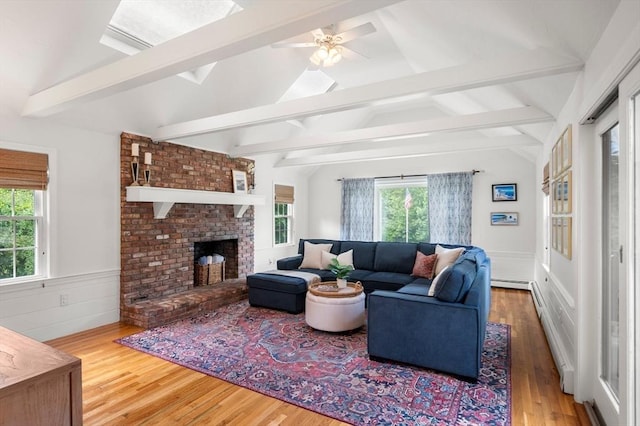 1051 Randolph Ave, Milton, MA 02186 - living room featuring wood finished floors, a wainscoted wall, baseboard heating, a ceiling fan, and a brick fireplace
