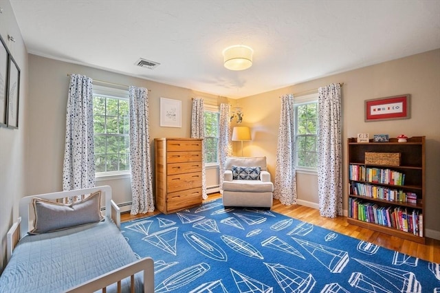 1051 Randolph Ave, Milton, MA 02186 - bedroom featuring multiple windows, wood finished floors, baseboards, and a baseboard heating unit