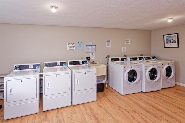 shared laundry area featuring baseboards, washing machine and dryer, and light wood-style floors