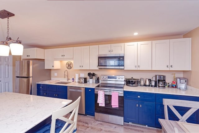 kitchen with decorative light fixtures, appliances with stainless steel finishes, white cabinets, a sink, and blue cabinets