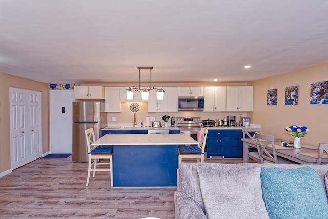 kitchen with white cabinetry, stainless steel appliances, light countertops, and a center island